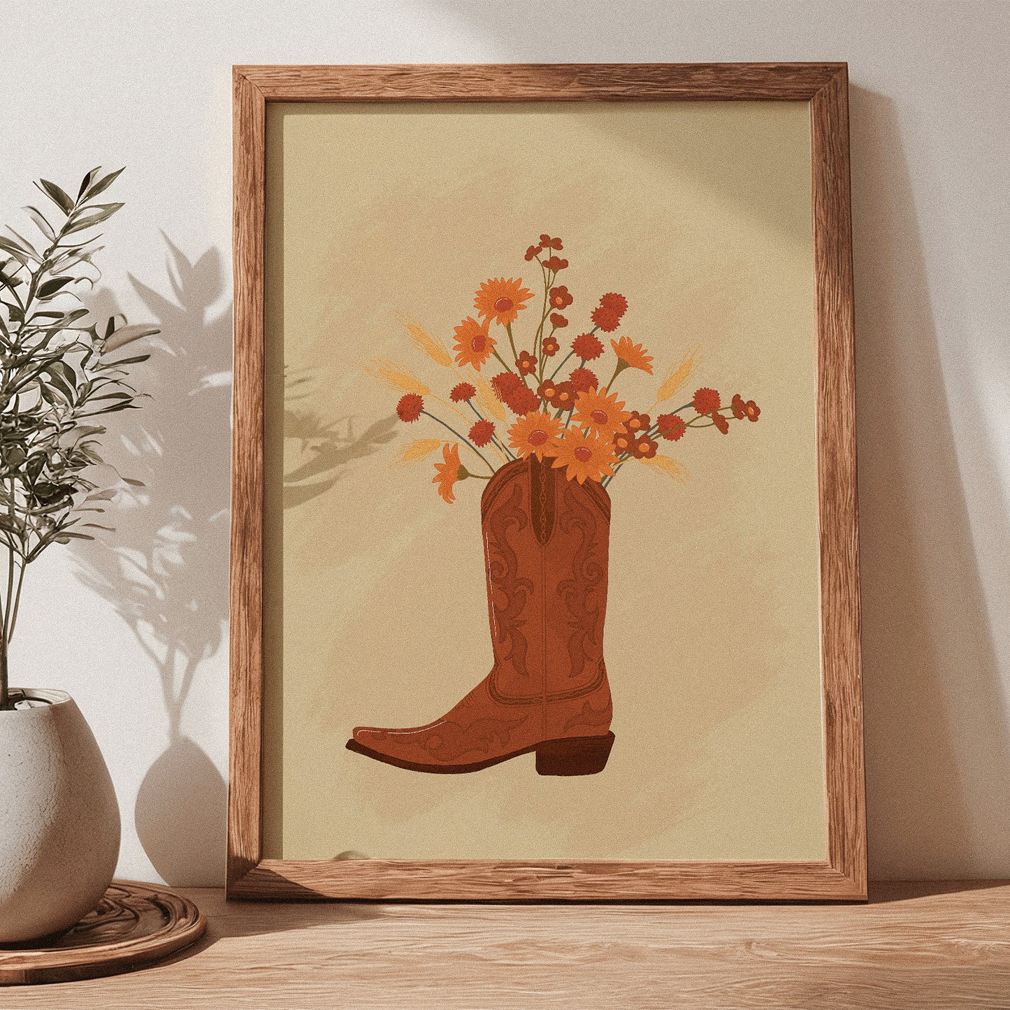 Framed artwork of a cowboy boot with flowers on a wooden shelf
