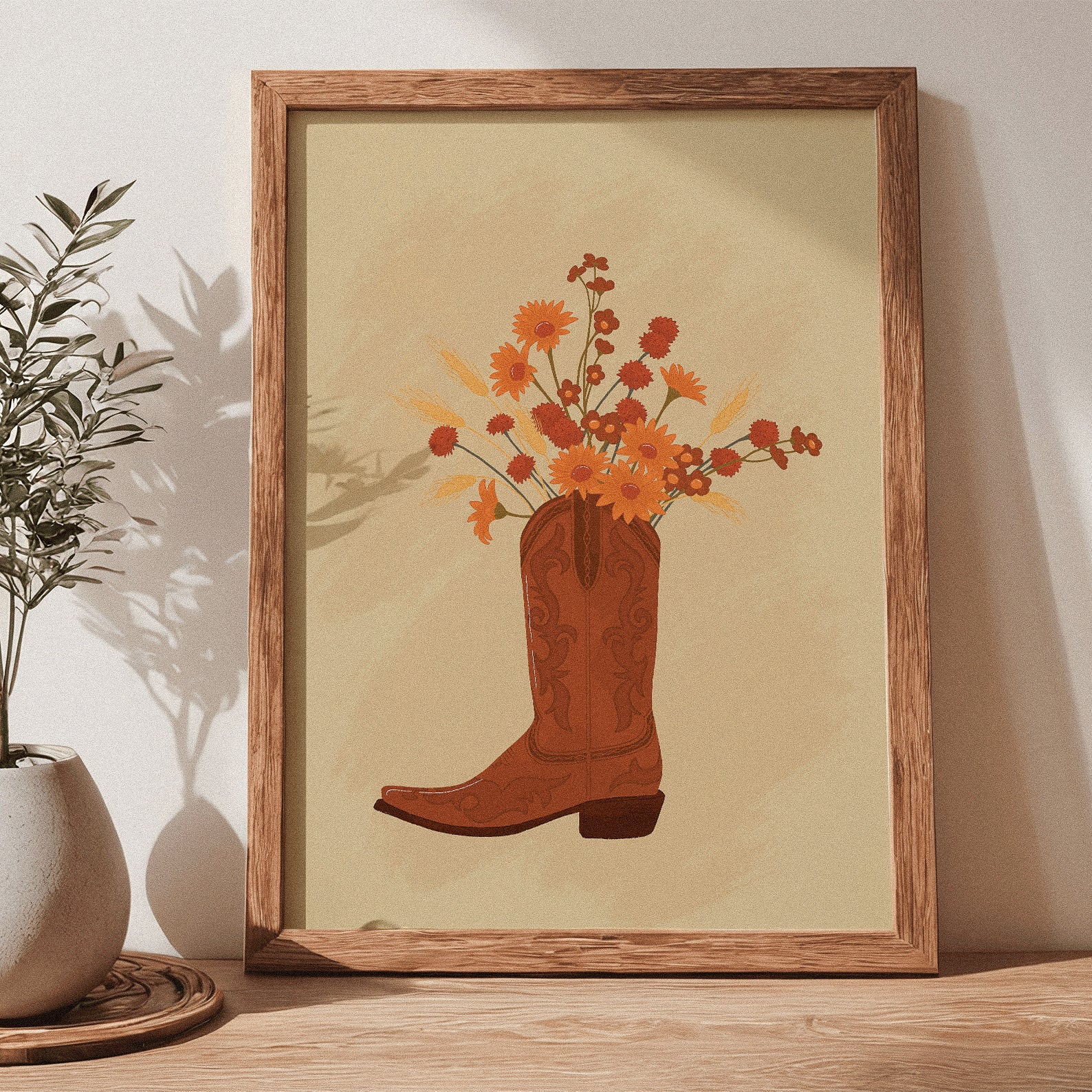 Framed artwork of a cowboy boot with flowers on a wooden shelf